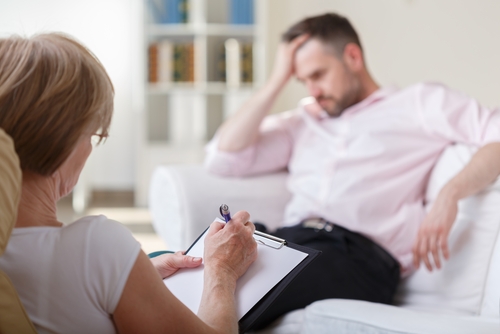 man holding head while in counseling